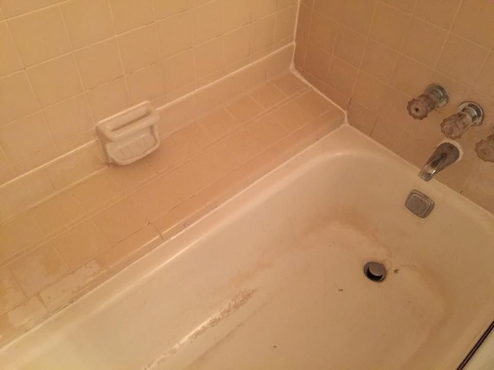 A bathtub in a bathroom with a soap dish on the wall.