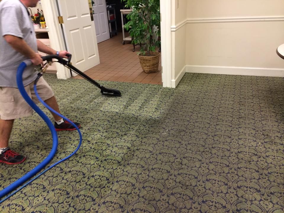 A man is cleaning a carpet with a vacuum cleaner