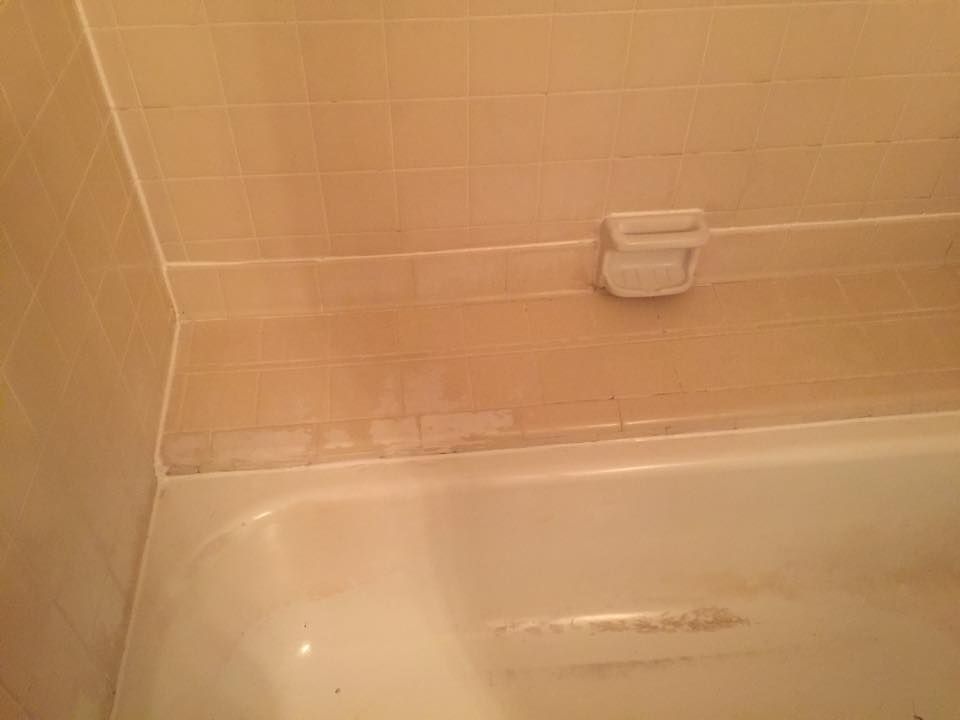 A bathtub in a bathroom with a soap dish on the wall.