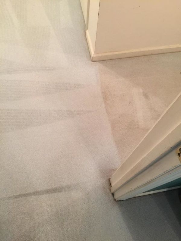 A white carpeted floor in a room next to a door.