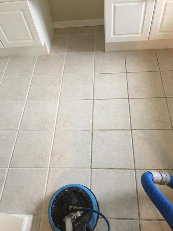 A vacuum cleaner is sitting on a tiled floor in a kitchen.