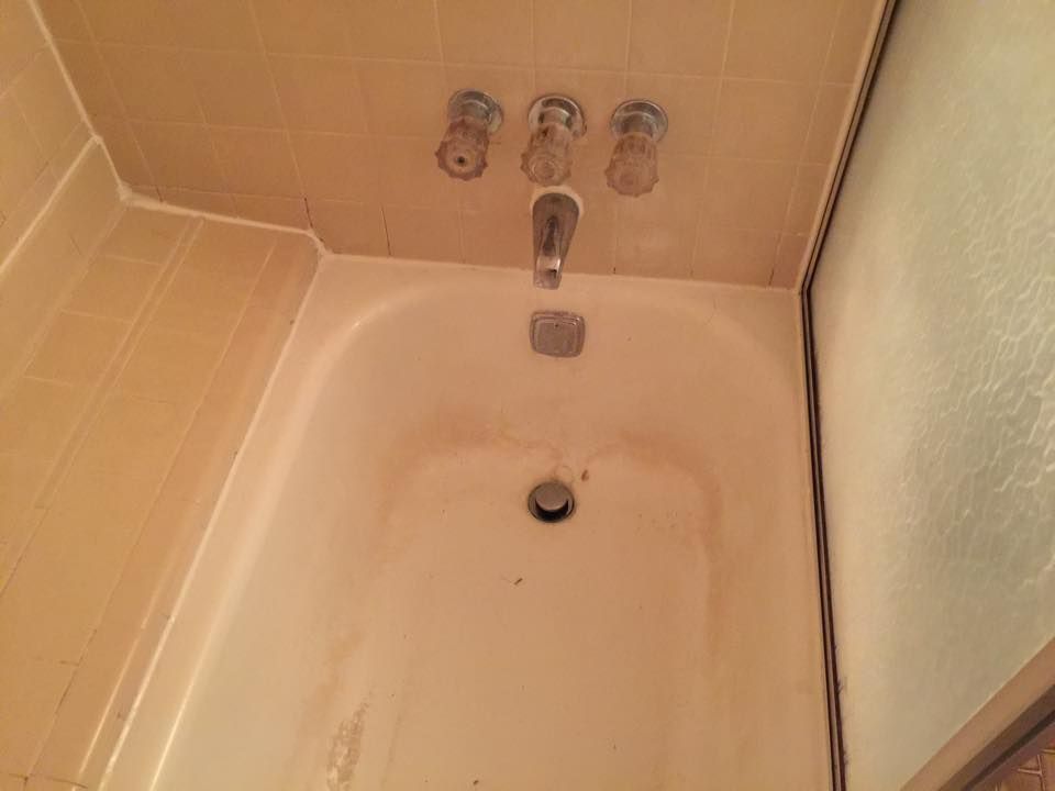 A bathtub in a bathroom with three faucets