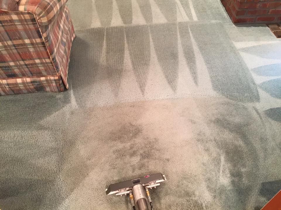 A vacuum cleaner is cleaning a carpet in a living room.