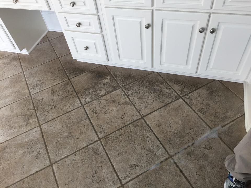 A kitchen with tile floors and white cabinets.