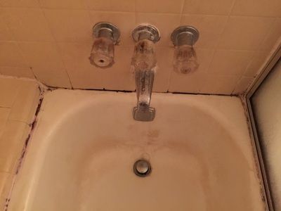A bathtub with a faucet and a sink in a bathroom.