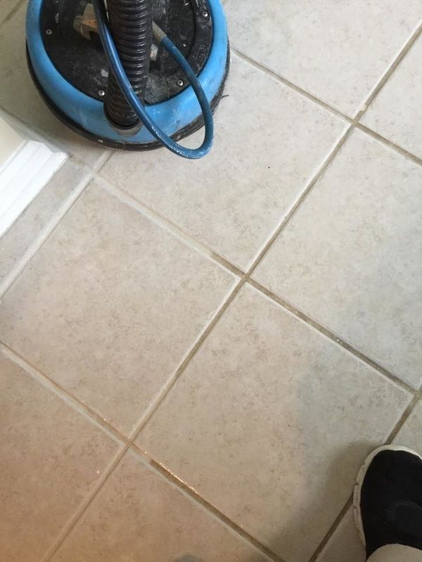 A person is standing on a tiled floor next to a vacuum cleaner.