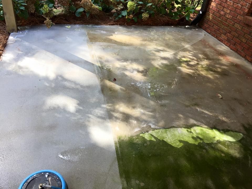 A before and after picture of a concrete patio being cleaned with a pressure washer.