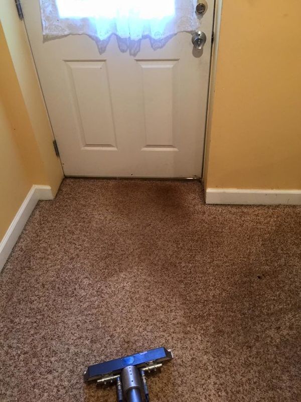 A vacuum cleaner is sitting on a carpeted floor next to a door.