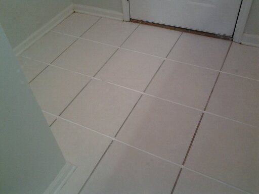 A white tile floor with a door in the background