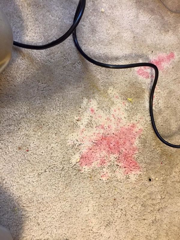 A close up of a carpet with a stain of red lipstick on it.