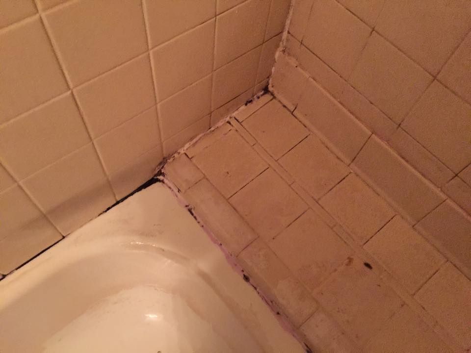 A bathtub is sitting next to a tiled wall in a bathroom.