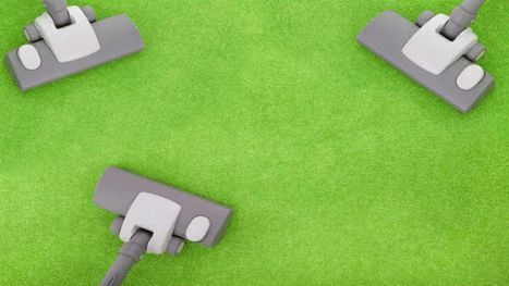 Three vacuum cleaners are sitting on a green carpet.