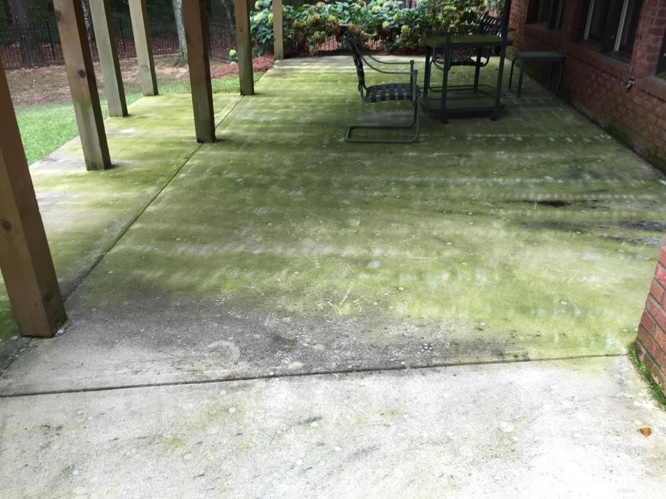 A patio with a table and chairs covered in green moss.