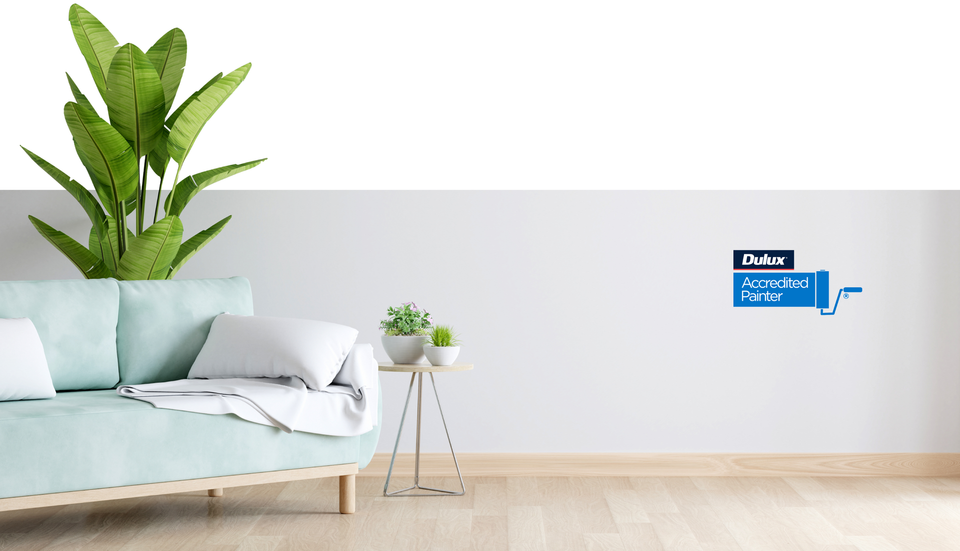 A living room with a couch and a plant on the wall.