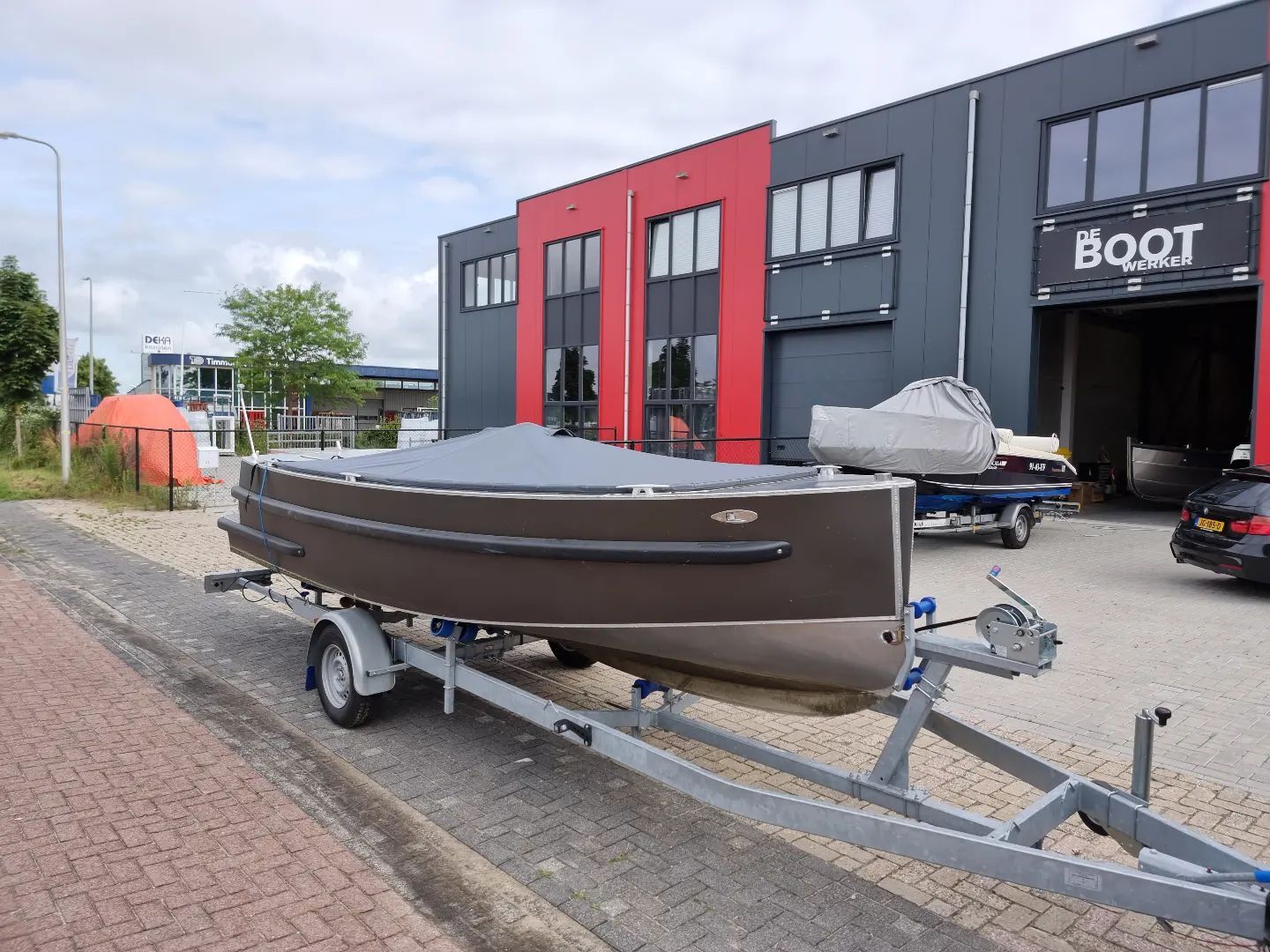 Een boot staat op een trailer voor een gebouw.