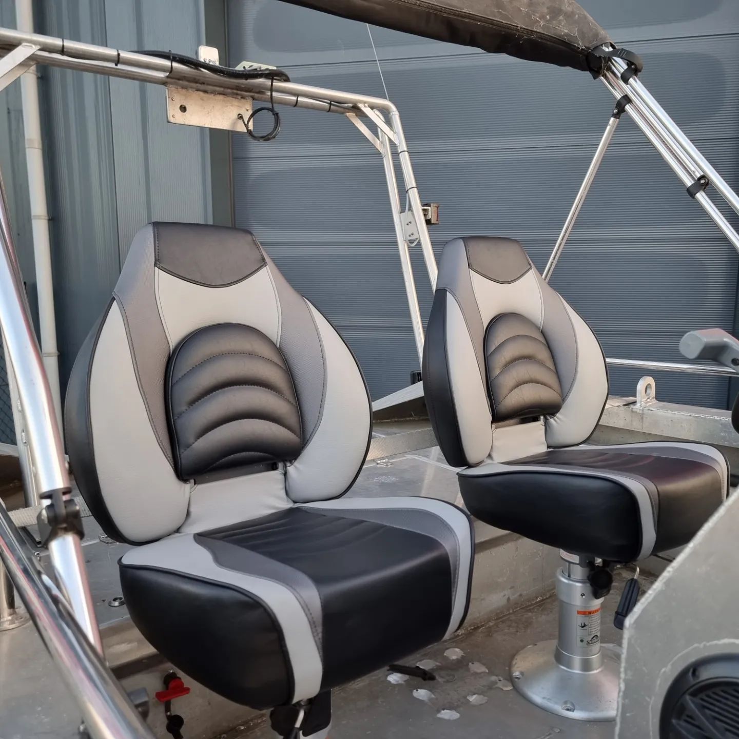 Twee zwarte en grijze stoelen op een boot met een luifel