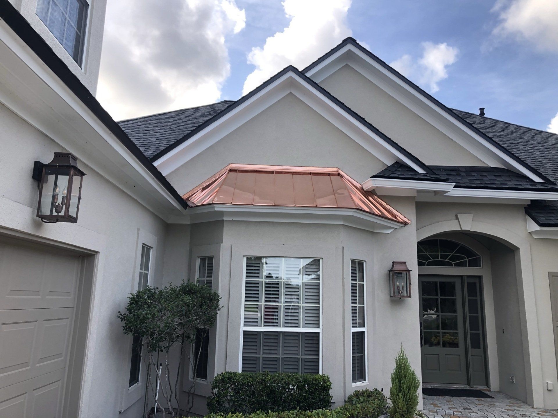The front of a white house with a copper roof