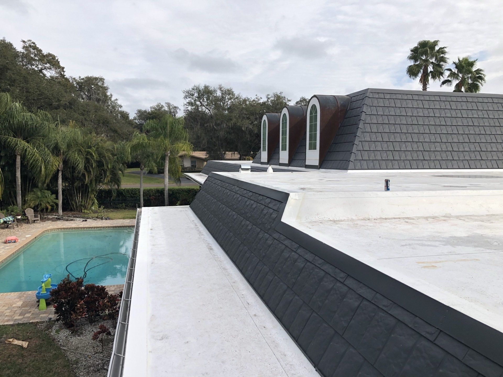 A roof with a swimming pool in the background