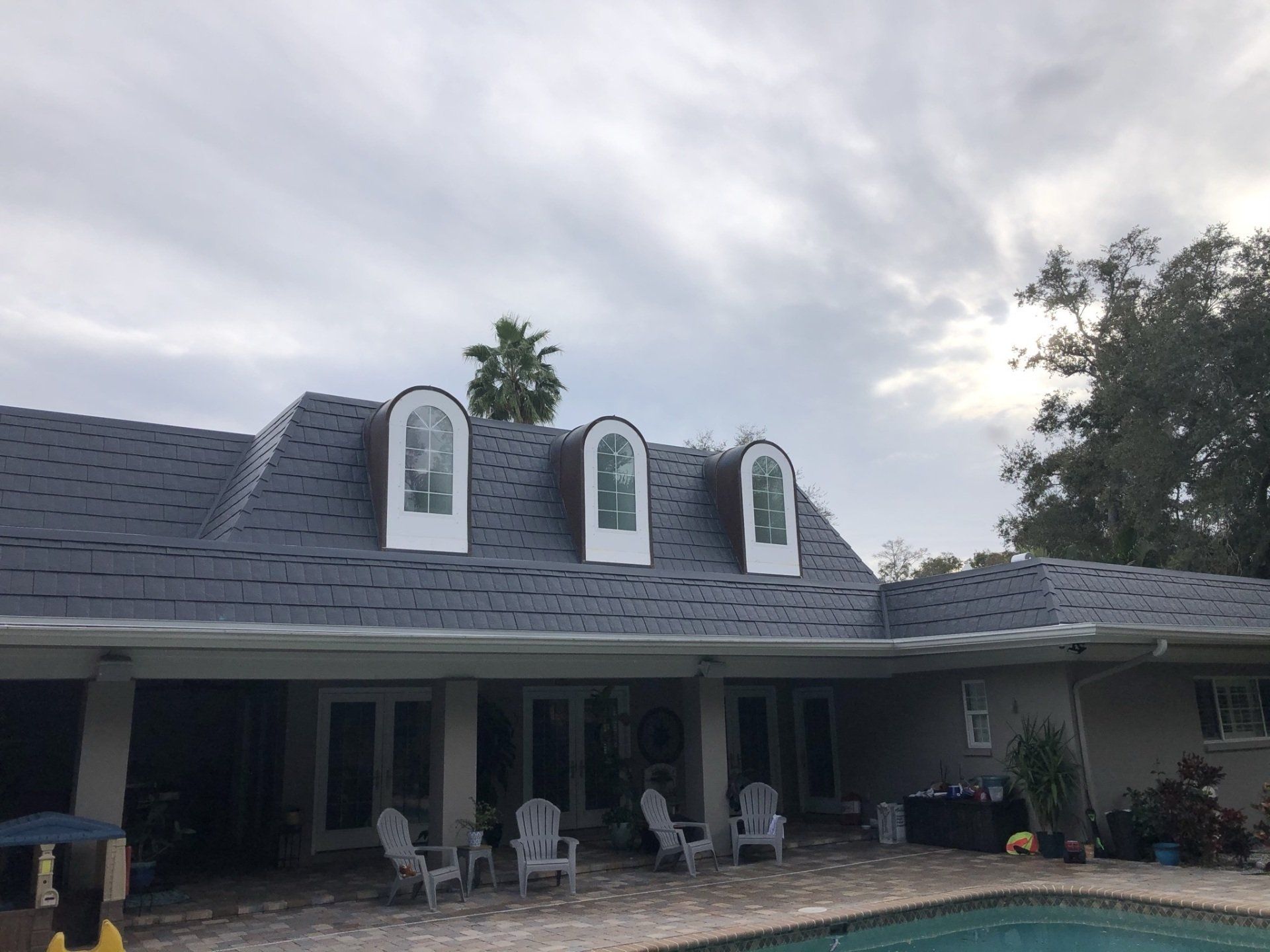 A large house with a pool and chairs in front of it.