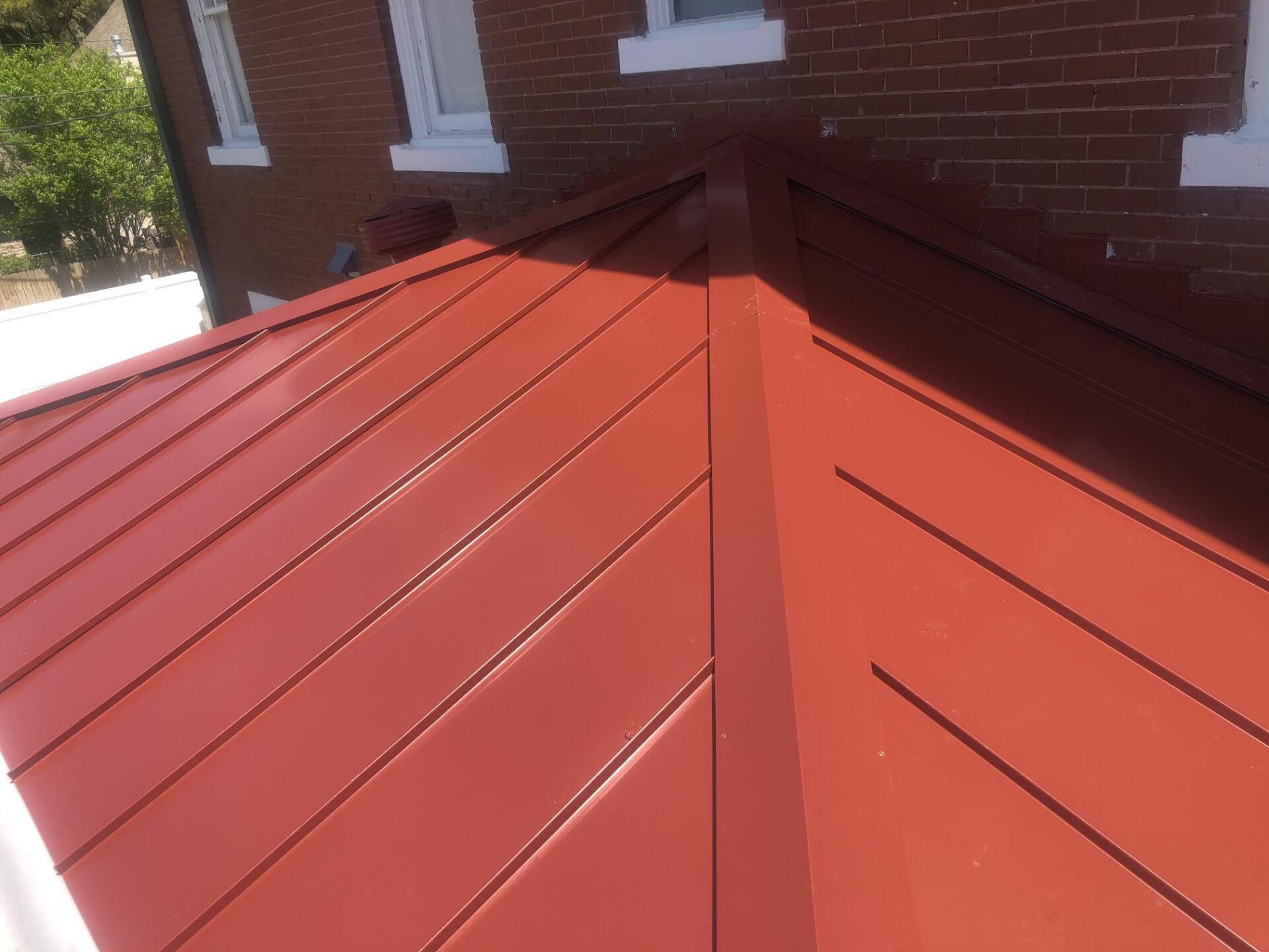 A red roof is sitting on top of a brick building.