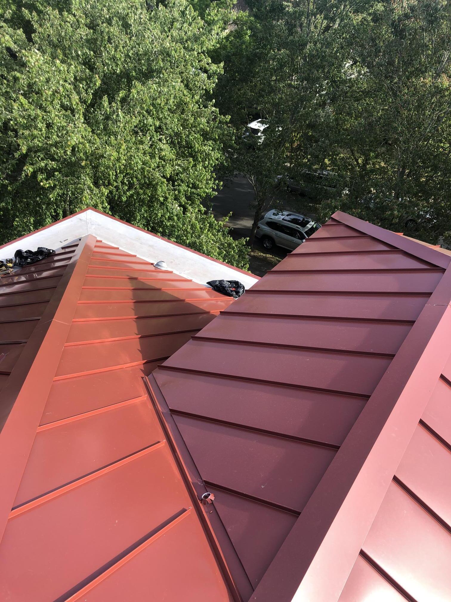 A close up of a red roof with trees in the background.