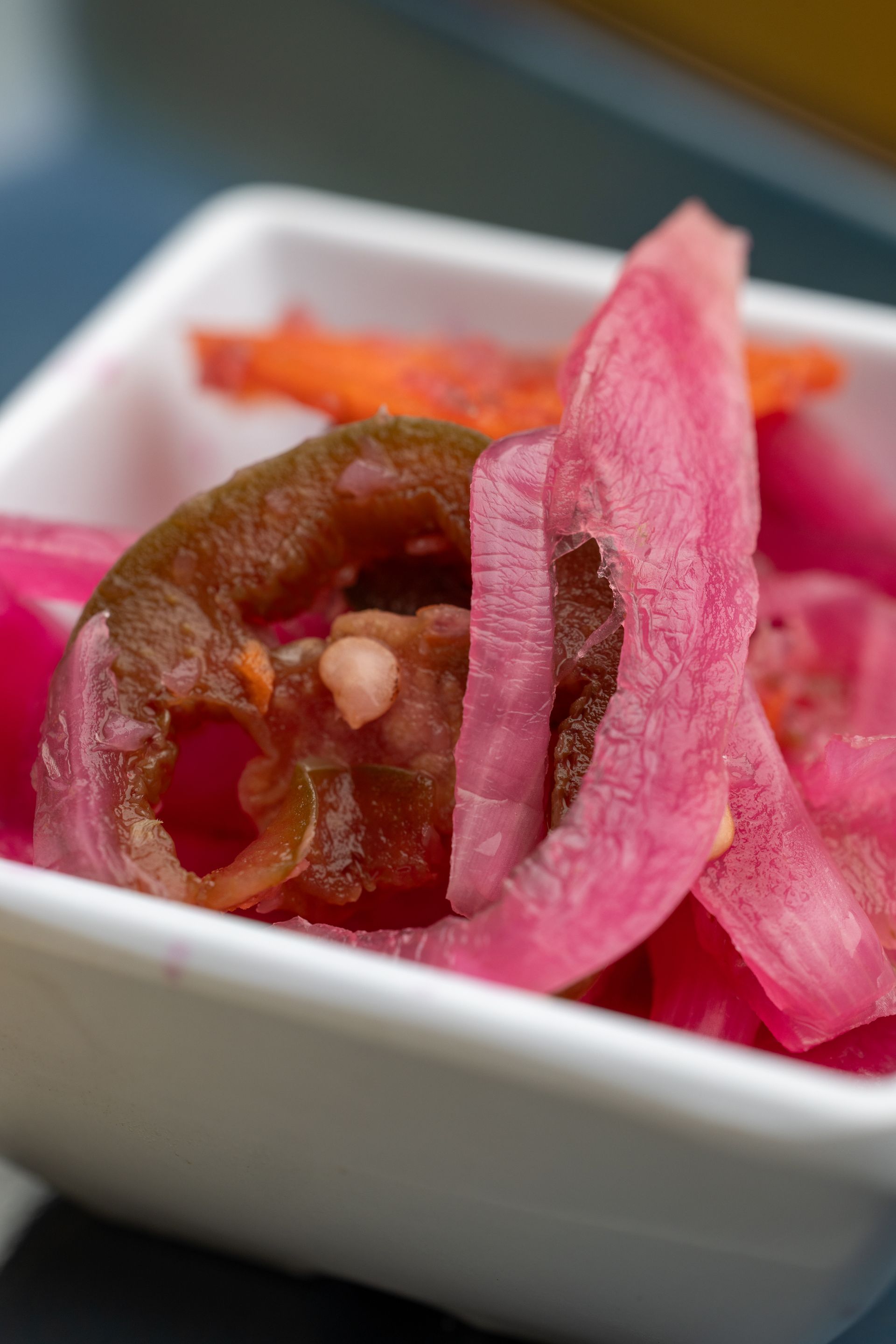 A close up of a bowl of pickled onions and carrots.