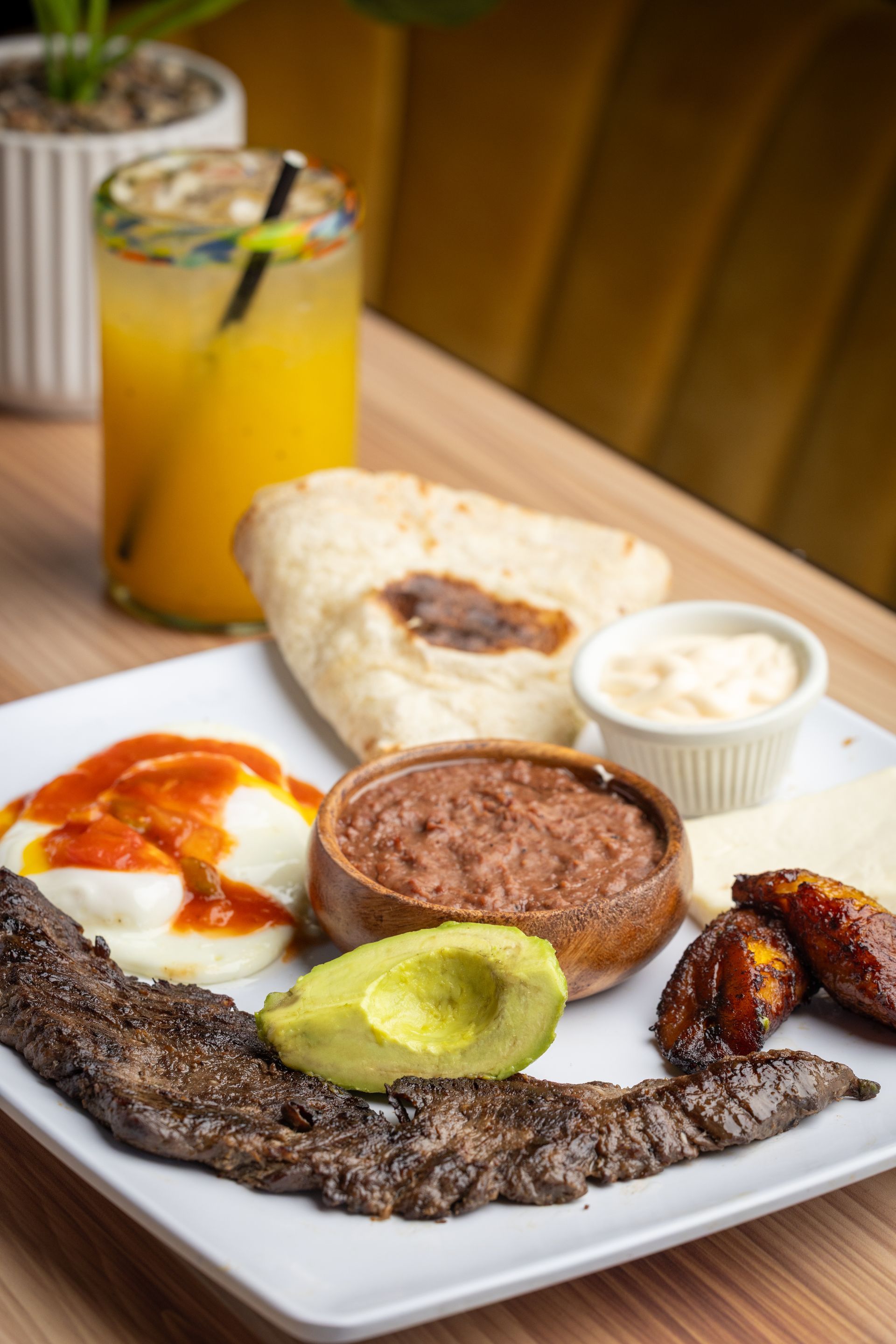 A white plate topped with a variety of food and a drink on a table.