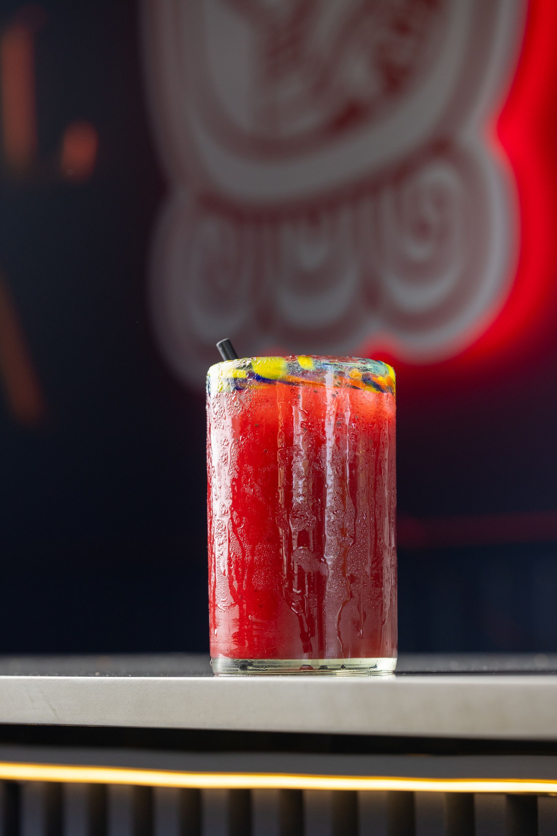 A close up of a red drink in a glass on a bar.
