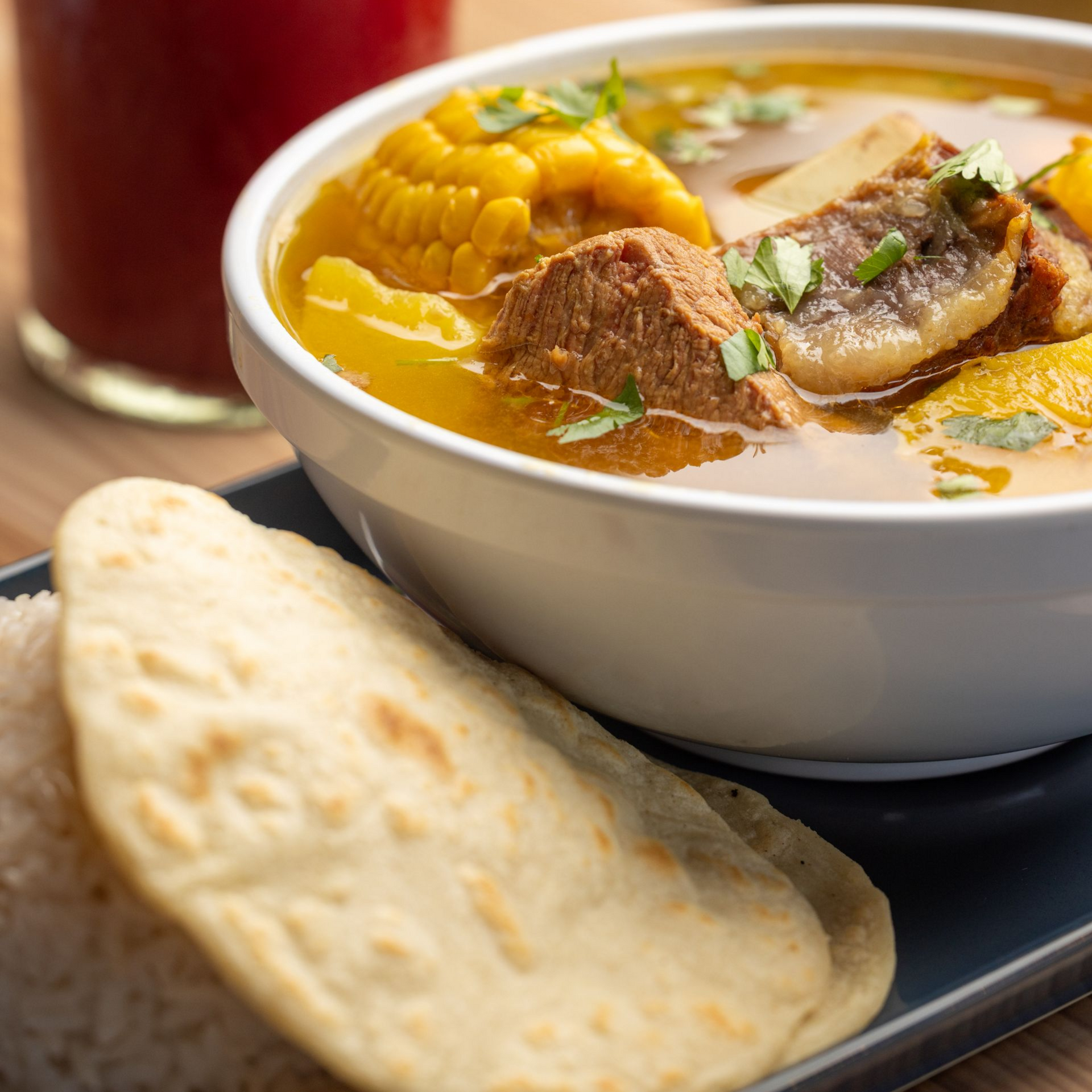 There is a bowl of soup and a drink on the table.