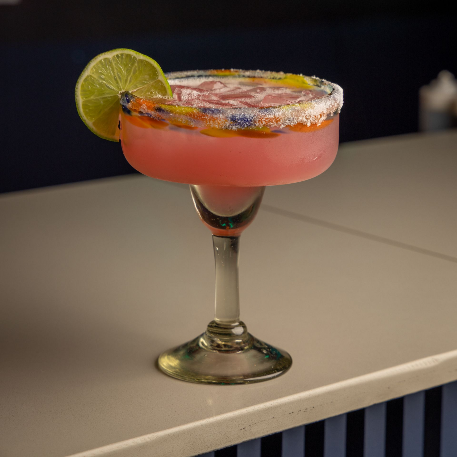 A close up of a glass of orange juice with a straw on a table.