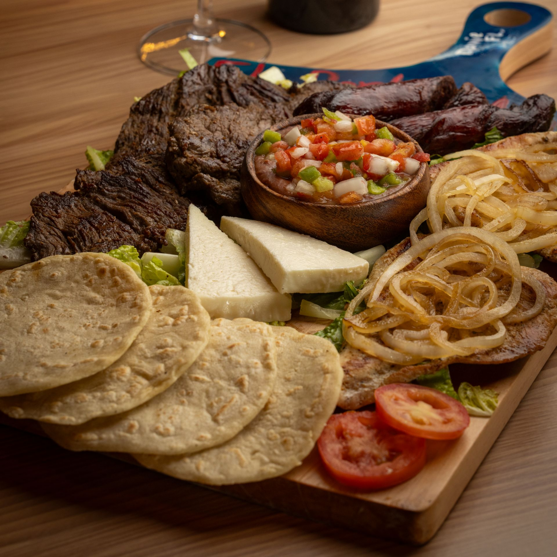 A plate of tacos and a glass of beer on a table.