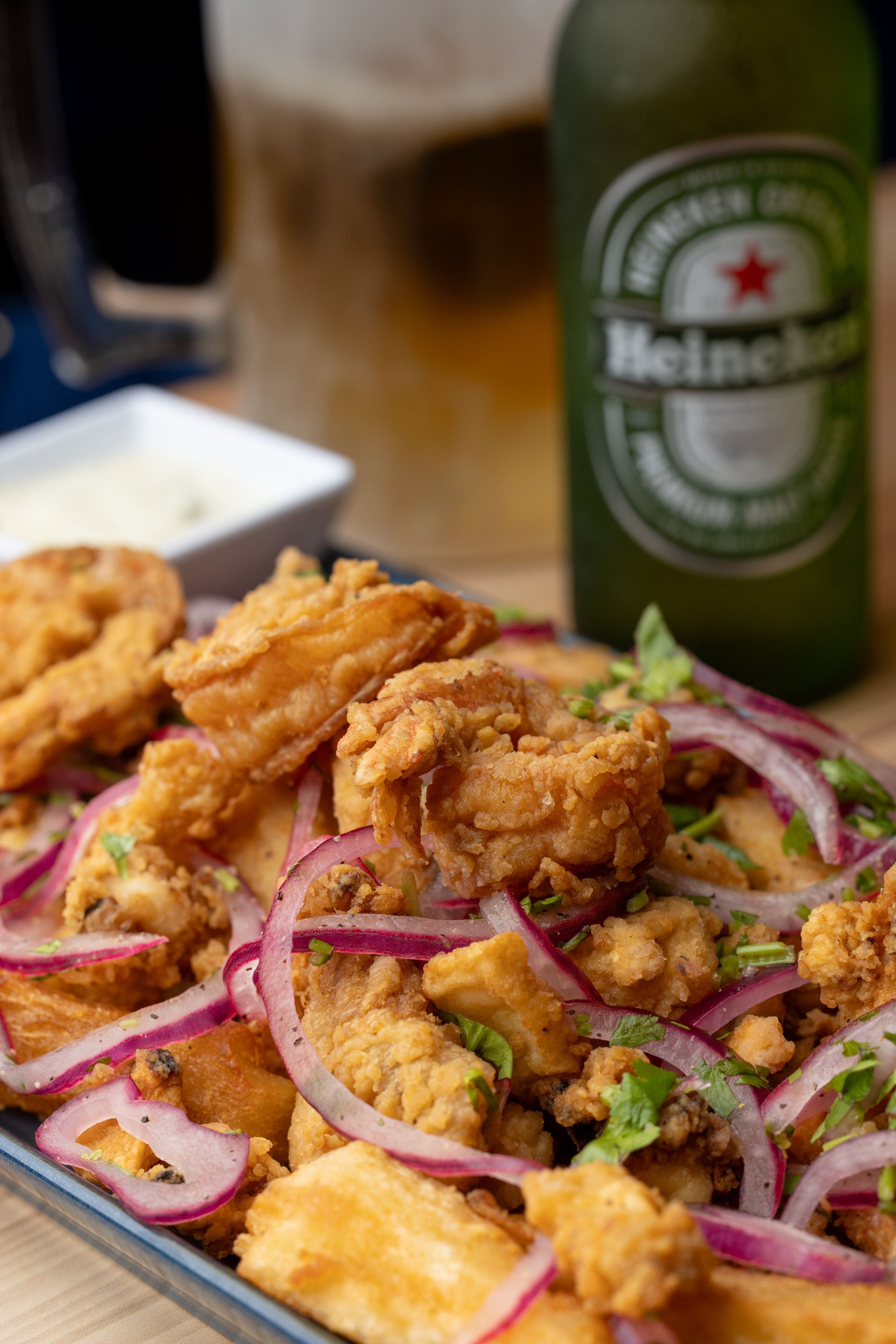 Fried seafood dish with red onions, cilantro, beer, and white sauce.