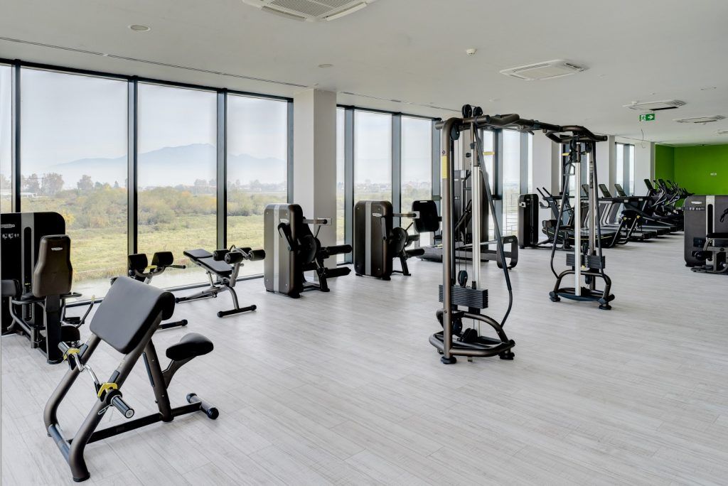 Velika teretana sa puno sprava za vežbanje i puno prozora.