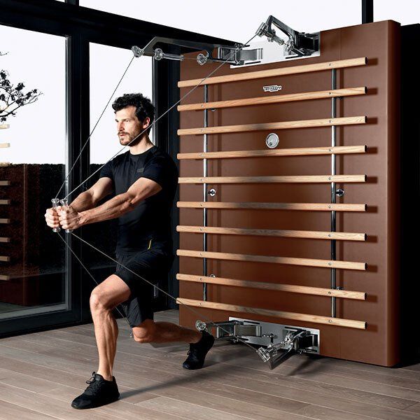 Muškarac radi vežbe na spravi u teretani.