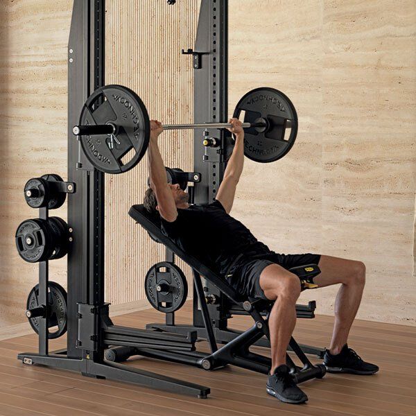 Covek sedi na klupi drzeci uteg iznad glave.