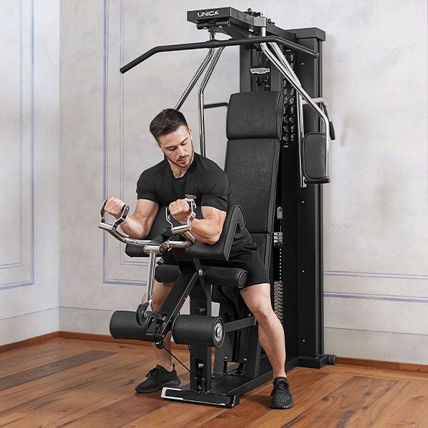 Čovek sedi na mašini u teretani.