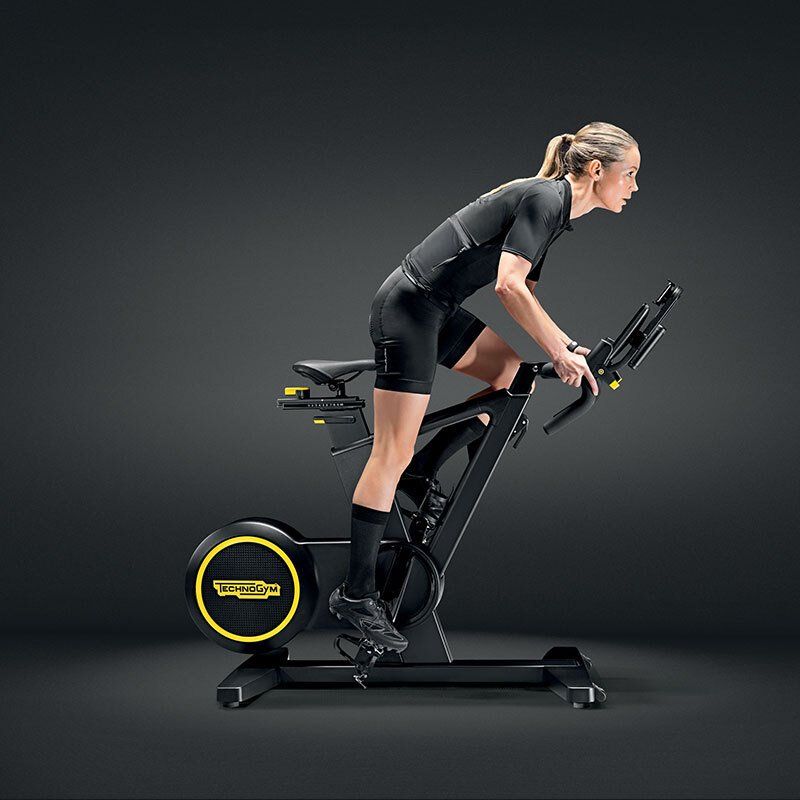 Žena vozi bicikl za vježbanje na crnoj pozadini.