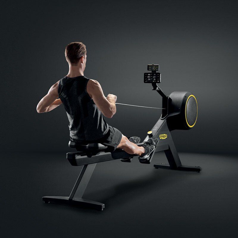 Muškarac sjedi na klupi i koristi spravu za veslanje.