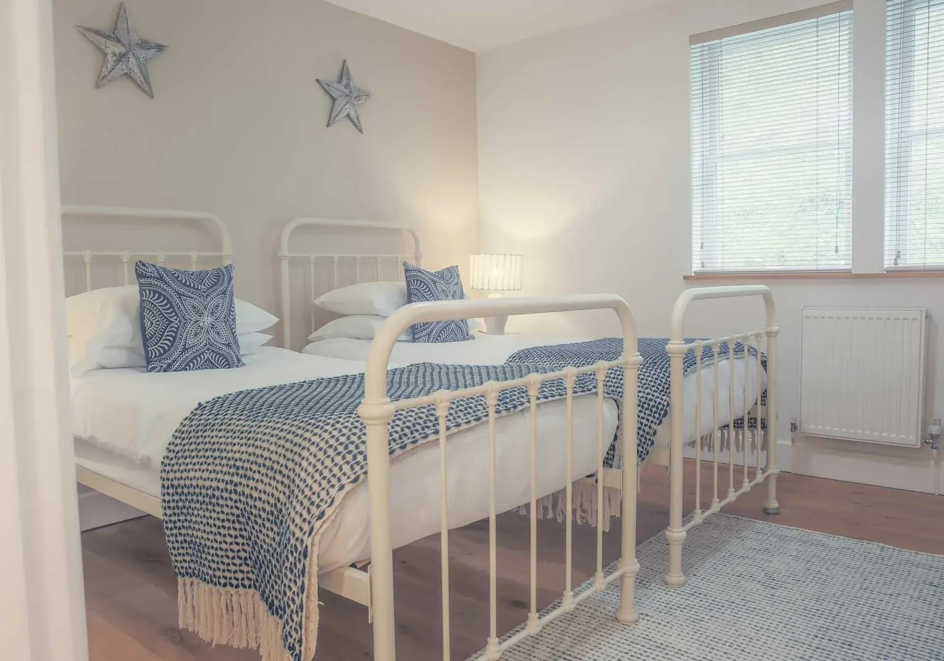 Two twin beds in a light room, blue and white decor, nautical theme.