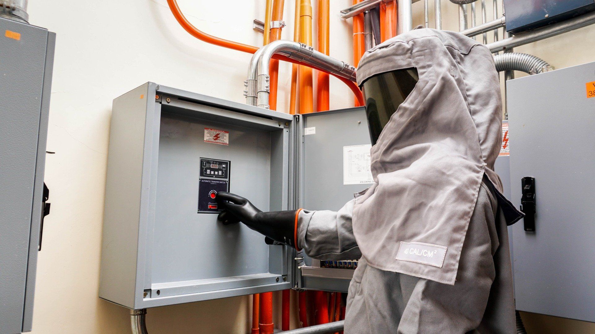 A man in a protective suit is working on an electrical box.