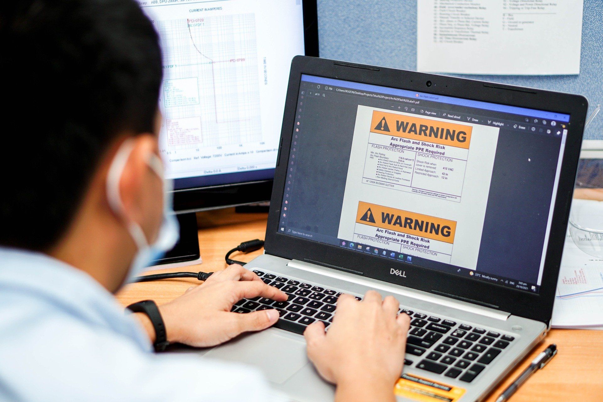 A man wearing a mask is typing on a laptop computer.