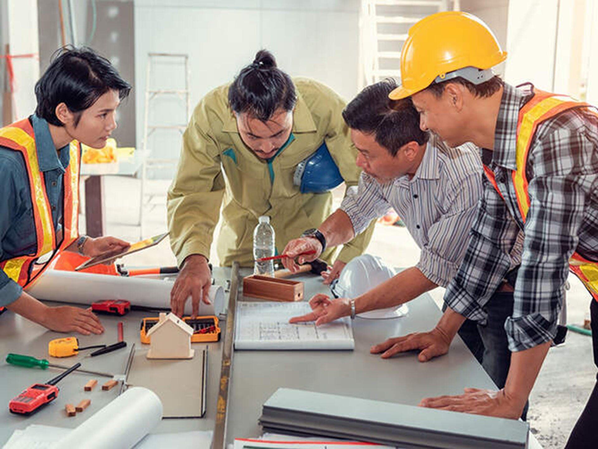 A group of people wearing hard hats and safety vests are standing around a blue box.