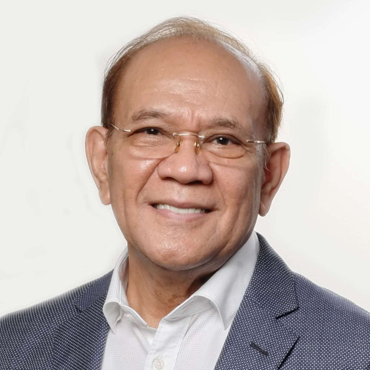 A man wearing glasses and a suit is smiling for the camera.