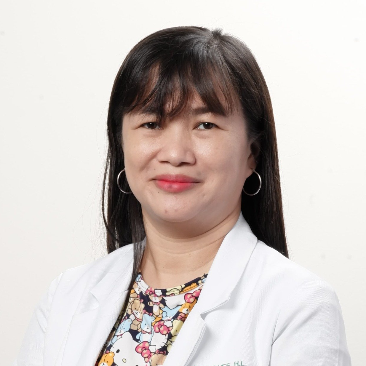 A woman in a white coat is smiling for the camera.