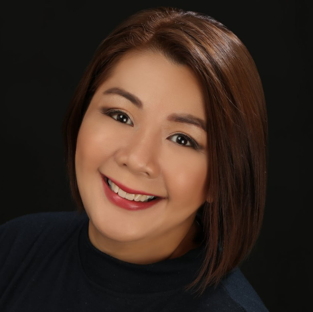 A woman with short brown hair is smiling and wearing a black shirt