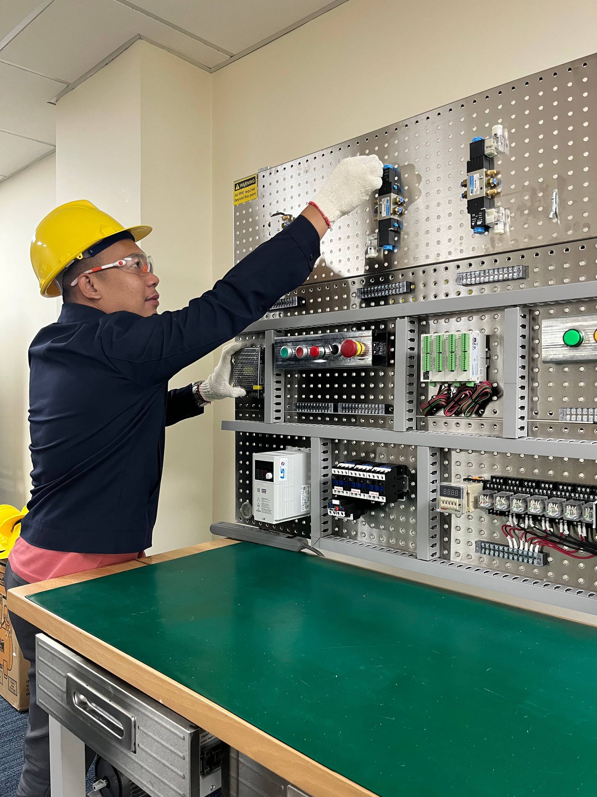 A man wearing a hard hat is working on a machine.
