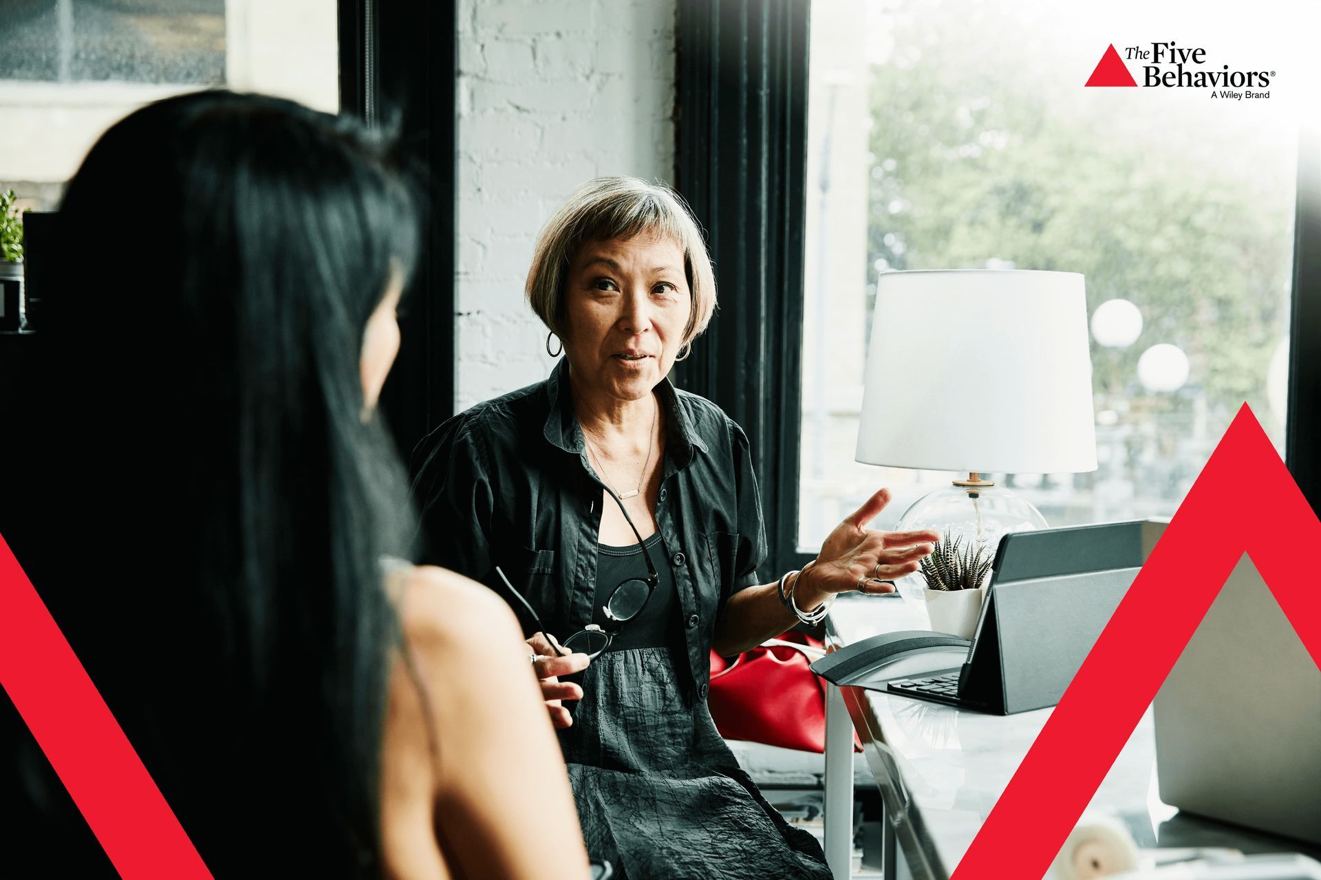 Two women are sitting at a table talking to each other.