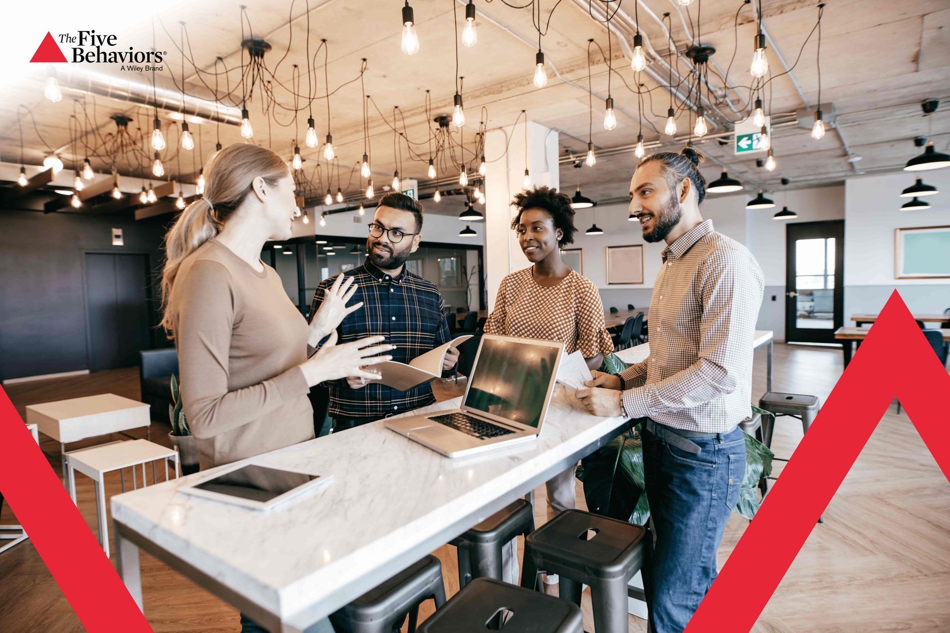 A group of people are standing around a table with laptops.