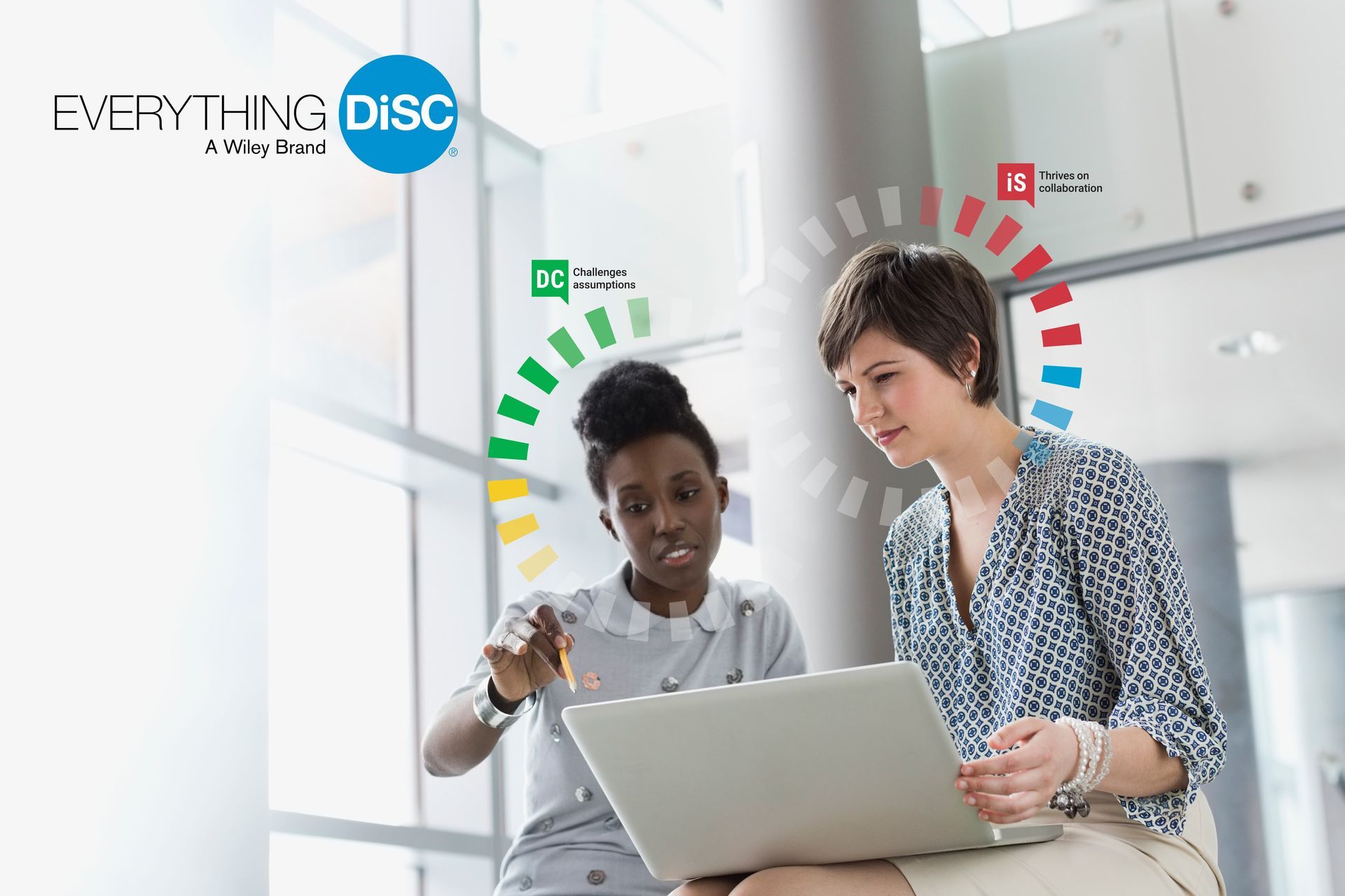 Two women are sitting in front of a laptop computer.