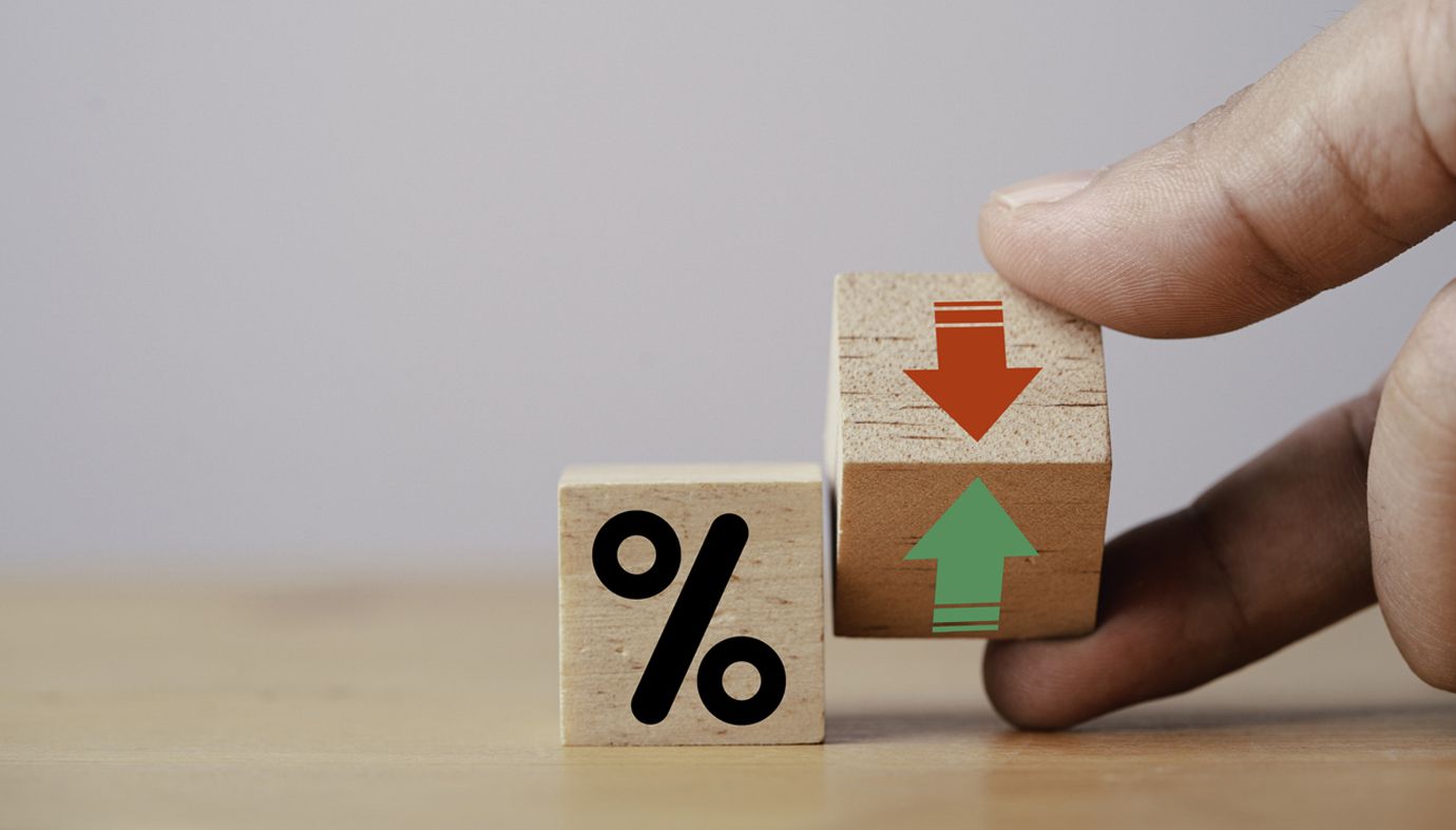 A person is holding a wooden block with a percent sign on it.